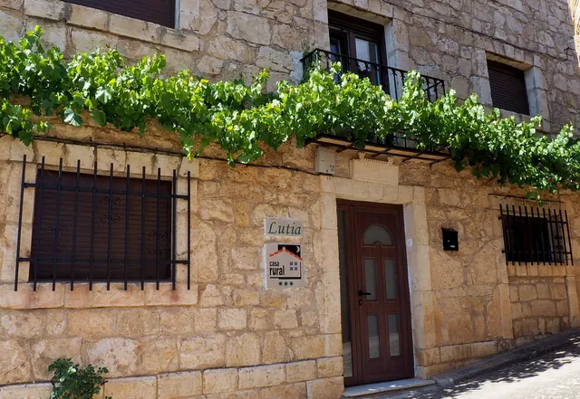 Fachada de Casa Rural Lutia desde la calle, con la placa y la parra