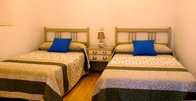 Dormitorio con dos camas y cojines azules