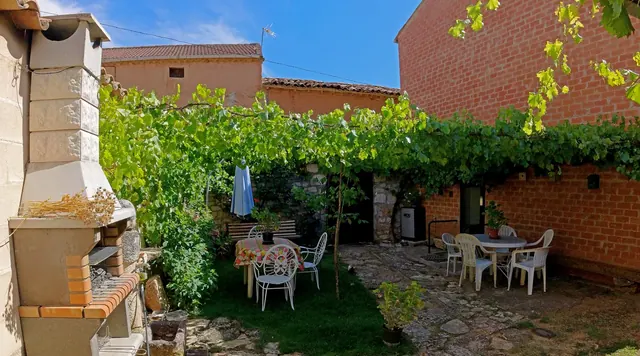 Patio con barbacoa de obra y jardín con parra