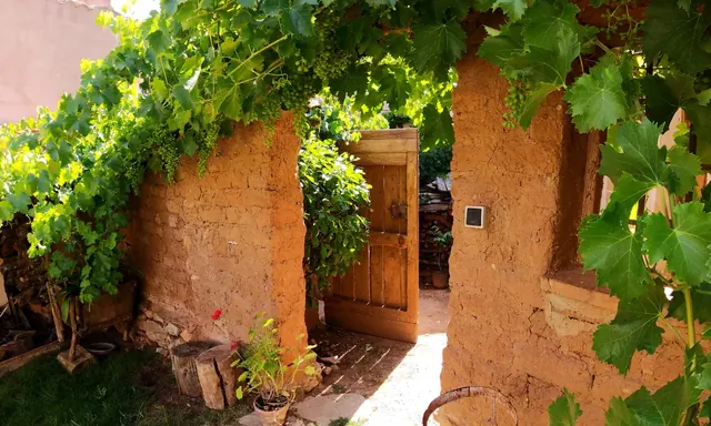 Paso entre muros de adobe cubierto por la parra